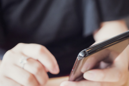 Woman with diamond ring on hand using smartphone in cafe restaurant