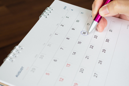 female hand holding pen circle mark on calendar pageの写真素材