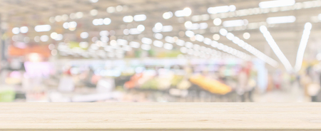 Wood table top with supermarket grocery store blurred defocused panorama background with bokeh light for product displayの写真素材