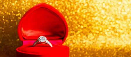 Jewelry diamond ring in gift box with abstract festive glitter Christmas holiday texture background blur with bokeh lightの写真素材