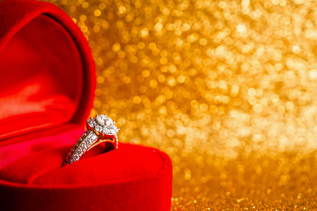 Jewelry diamond ring in gift box with abstract festive glitter Christmas holiday texture background blur with bokeh lightの写真素材