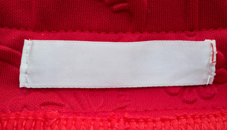 blank white clothing label on red fabric texture background