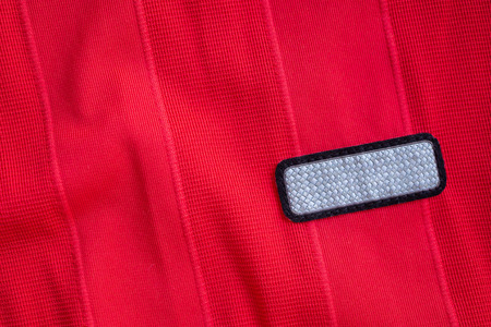 blank clothes tag label on red polyester sport jersey shirt texture background
