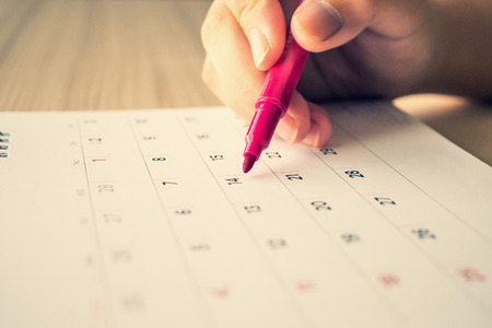 Hand with pen writing on calendar page closeupの写真素材