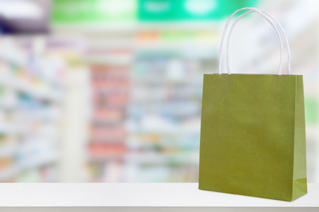 Paper bag on Pharmacy drugstore counter table with medicine and healthcare product on shelves blur backgroundの写真素材