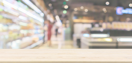 Empty wood table top with abstract supermarket aisle interior blurred defocused background with bokeh lightの写真素材