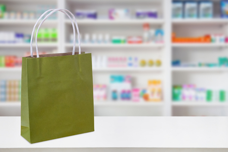 Paper bag on Pharmacy drugstore counter table with medicine and healthcare product on shelves blur backgroundの写真素材