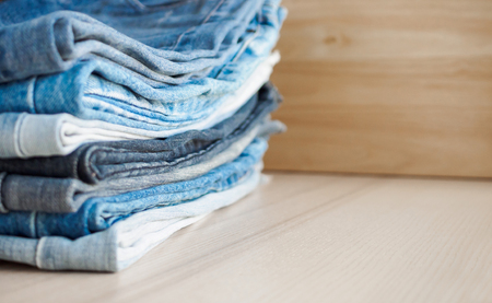 denim blue jeans stack on wood table backgroundの写真素材