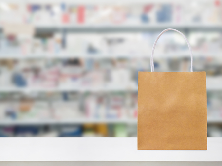 Paper bag on Pharmacy drugstore counter table with medicine and healthcare product on shelves blur backgroundの写真素材