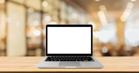 Blank screen laptop computer on wood table top with blur cafe restaurant with abstract bokeh light defocused backgroundの写真素材