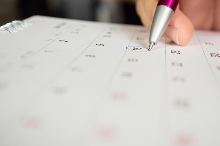 female hand holding pen circle mark on calendar pageの写真素材