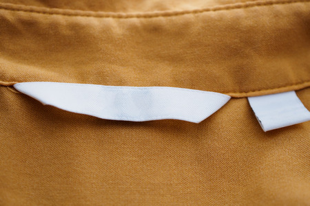 White blank clothing label on brown shirt background