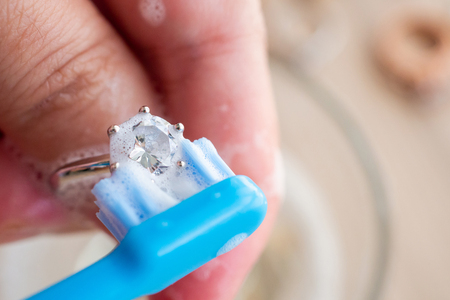 Jeweller hand cleaning and polishing vintage jewelry diamond ring closeupの写真素材