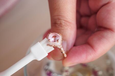 Jeweller hand cleaning and polishing vintage jewelry diamond ring closeup