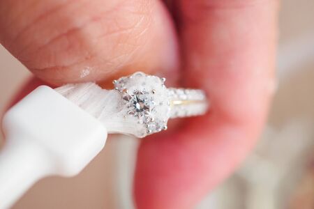 Jeweller hand cleaning and polishing vintage jewelry diamond ring closeup macroの写真素材