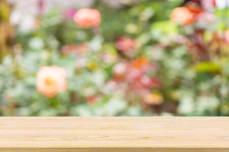 Empty wood table top with abstract blur colorful rose flowers in the garden natural bokeh light...