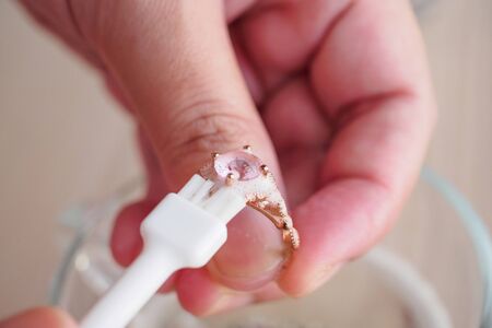 Jeweller hand cleaning and polishing vintage jewelry diamond ring closeupの写真素材