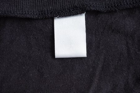 Blank white laundry care clothing label on black fabric textureの写真素材