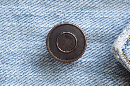 Metal button on blue denim jeans background