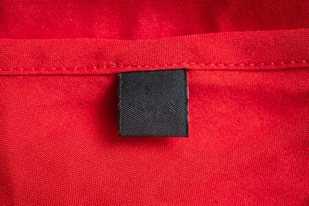 Blank black laundry care clothing label on red color fabric textureの写真素材