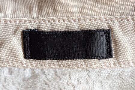 Blank black laundry care clothing label on fabric texture