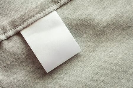 White blank laundry care clothing label on gray fabric texture backgroundの写真素材