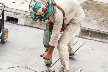 Construction worker using jackhammer drilling concrete surface