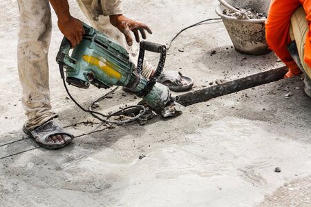 Construction worker using jackhammer drilling concrete surface