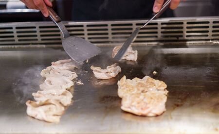 Japanese chef cooking meat in teppanyaki restaurantの写真素材