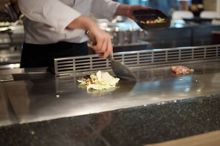 Japanese chef cooking meat in teppanyaki restaurantの写真素材