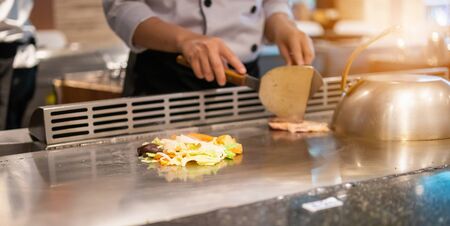 Japanese chef cooking meat in teppanyaki restaurantの写真素材