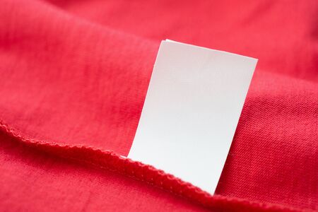 White laundry care washing instructions clothes label on red cotton shirtの写真素材