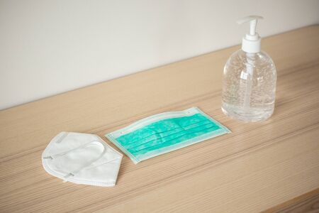 Medical face mask with alcohol sanitizer gel hand wash on wood table for covid-19 Coronavirus prevention conceptの写真素材