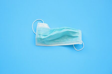 Disposable surgical face mask on blue background protection against COVID-19 coronavirus. Healthcare...