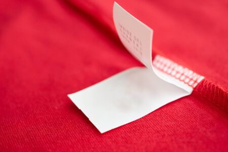 White laundry care washing instructions clothes label on red cotton shirt