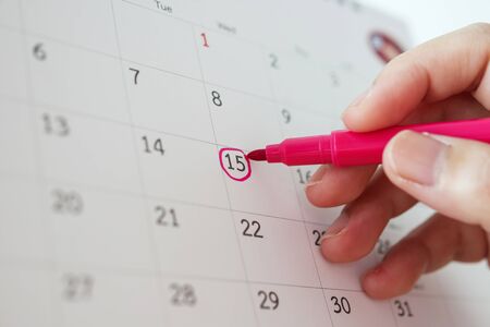 Hand with pen mark at 15th on calendar dateの写真素材