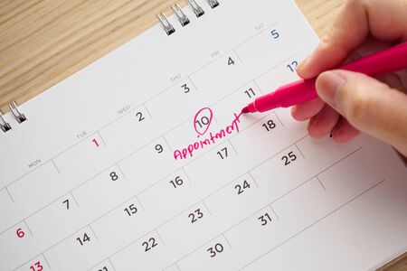 Hand with pen writing on calendar date appointment conceptの写真素材