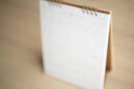 Blur calendar page close up on wood table background business planning appointment meeting concept