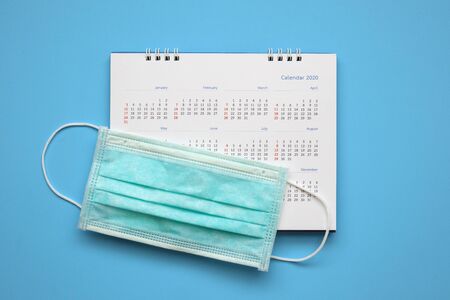 Surgical face mask on 2020 calendar page on blue background Year of Covid-19 Coronavirus prevention conceptの写真素材