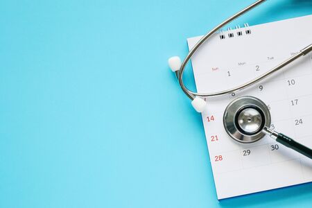 Stethoscope with calendar page date on blue background doctor appointment medical conceptの写真素材