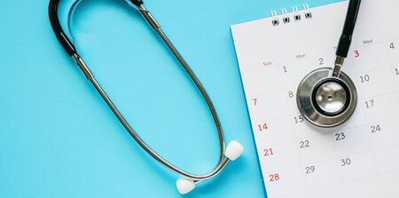 Stethoscope with calendar page date on blue background doctor appointment medical conceptの写真素材