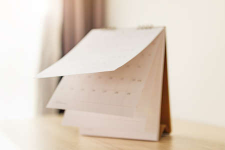Blur Calendar page flipping sheet on wood table background business schedule planning appointment meeting conceptの写真素材