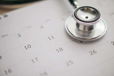 Stethoscope with calendar page date on wood table background doctor appointment medical conceptの写真素材