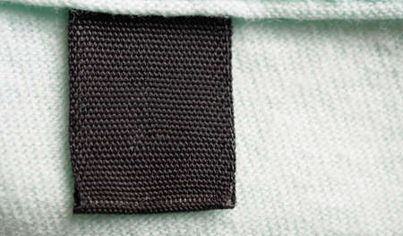 Black blank laundry care clothes label on cotton shirt backgroundの写真素材