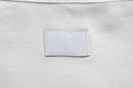 White blank laundry care clothes label on cotton shirt background