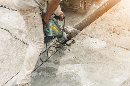 Construction worker using jackhammer drilling concrete surfaceの写真素材