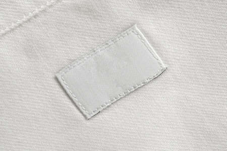White blank laundry care clothes label on cotton shirt background