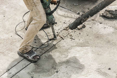 Construction worker using jackhammer drilling concrete surfaceの写真素材