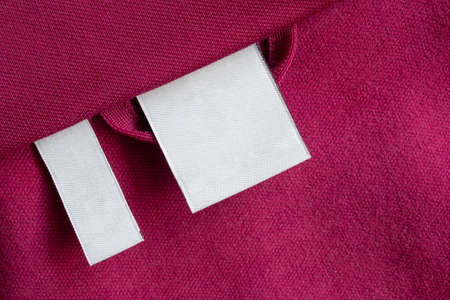 Blank white laundry care clothes label on red fabric texture backgroundの写真素材