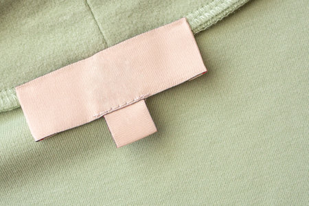 Blank laundry care clothes label on green fabric texture background